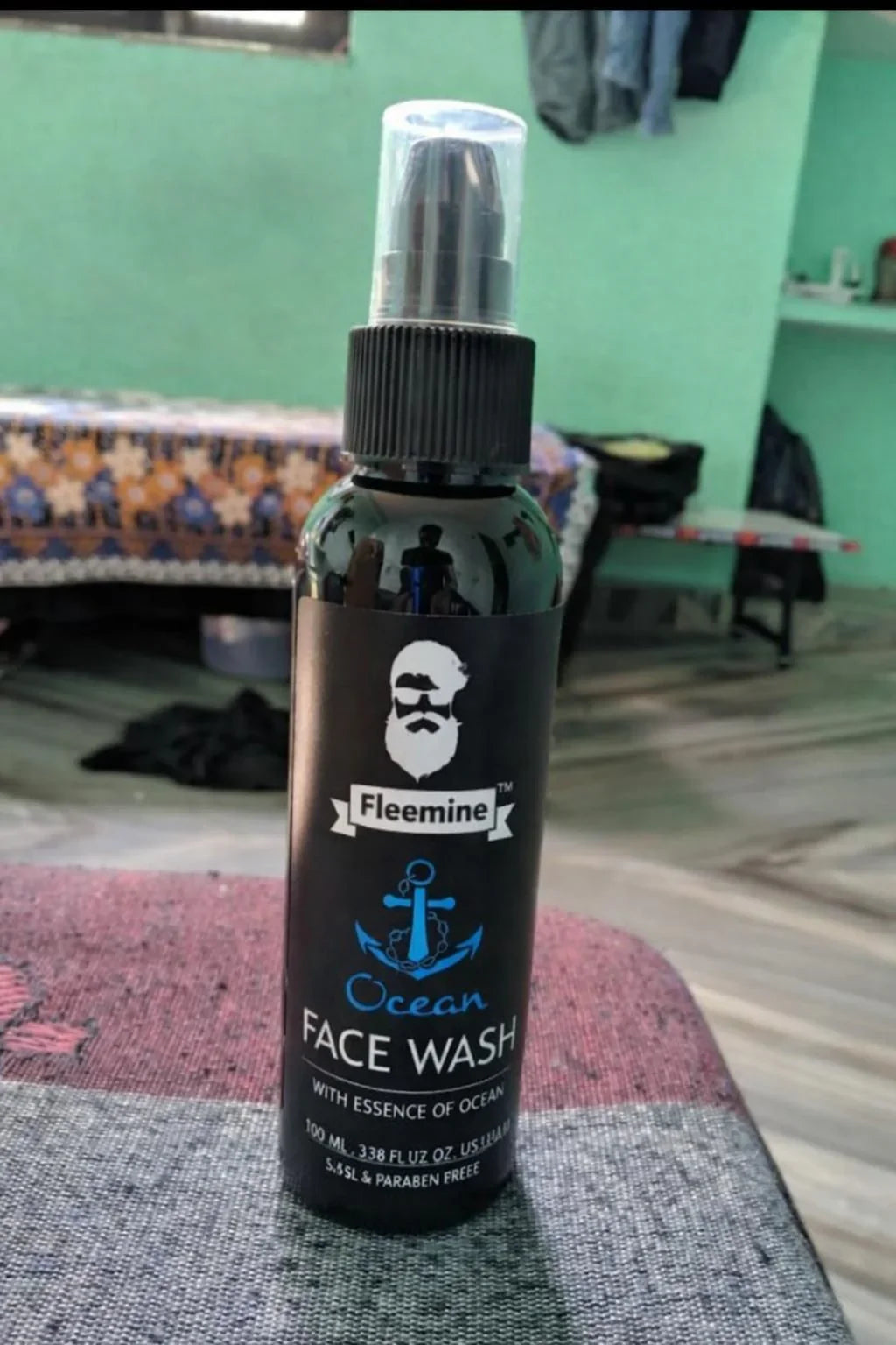 Fleemine Ocean face wash bottle with anchor logo on table in a room with green walls