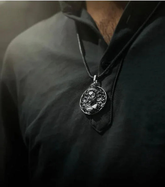 Close-up of man wearing black shirt with round engraved pendant necklace